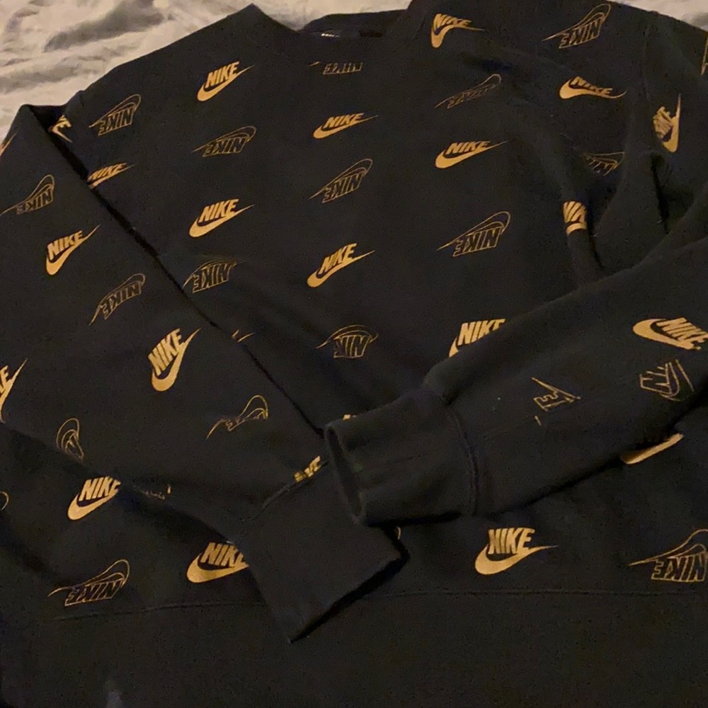 A thick NIKE gold & black sweater .